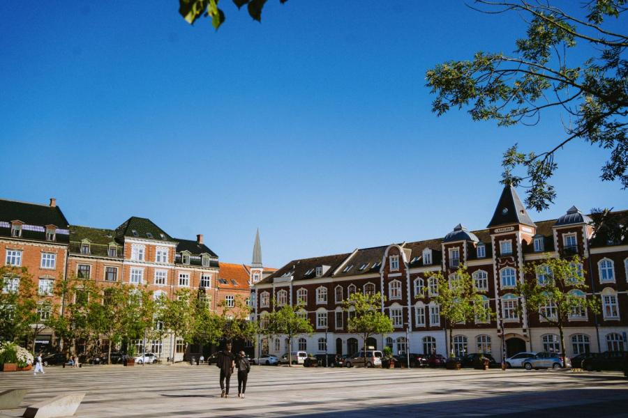 To personer går over Axeltorv med gamle fleretagers huse i baggrunden
